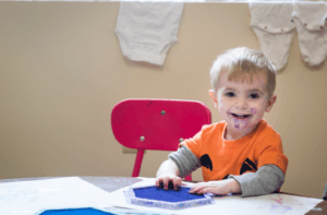 Young child playing with blue ink in the classroom