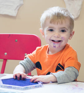 Young child playing with blue ink in the classroom