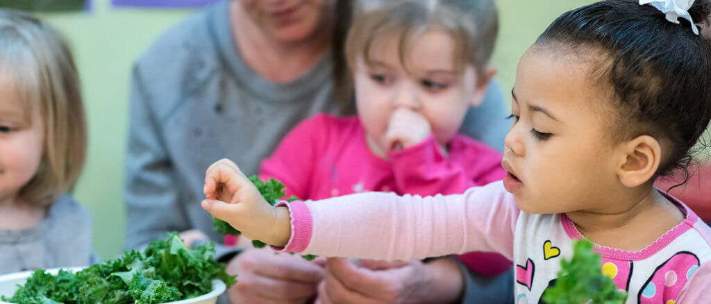 Children sitting together playing with fresh greens