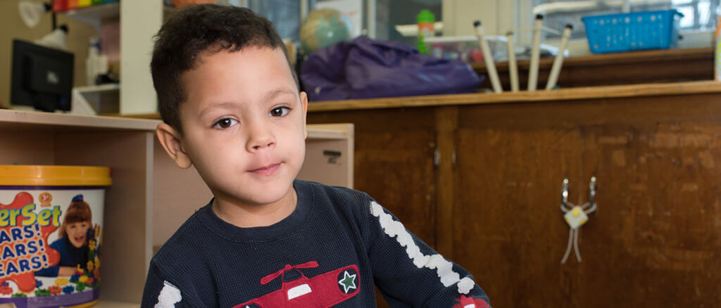 Young child in a classroom looking at the camera