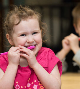 Young child brushing her teeth with a pink toothbrush