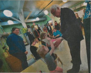 Harlequinn, a little girl enrolled at EES, joyfully shows Bernie Sanders her artwork in this photo from the Bennington Banner