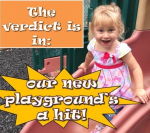 A little girl smiles excitedly at the camera while standing on top of a slide in our new playground. The text around her reads: "the verdict is in: our new playground's a hit!"