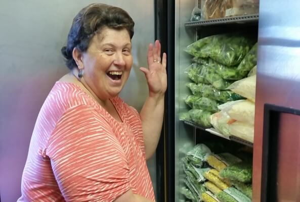 A photo of Pat smiling next to a refrigerator stocked with food.