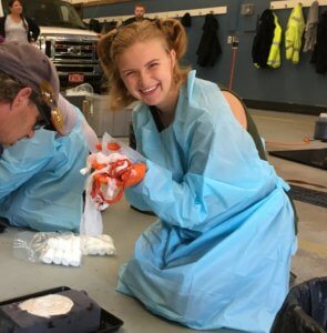 A young woman smiles as she holds bundle of gauze used in a bleeding emergency simulation