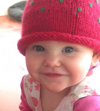 smiling baby in red knitted berry hat